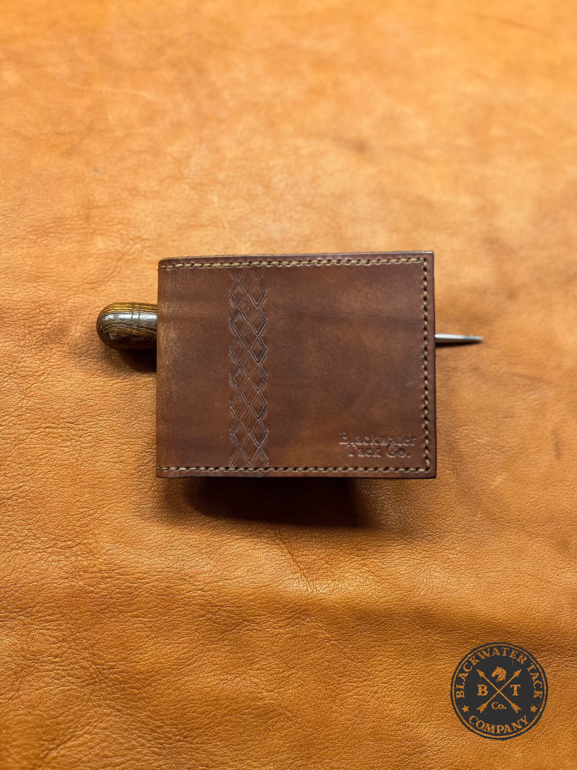 a closed brown bi-fold wallet with a diamond pattern 