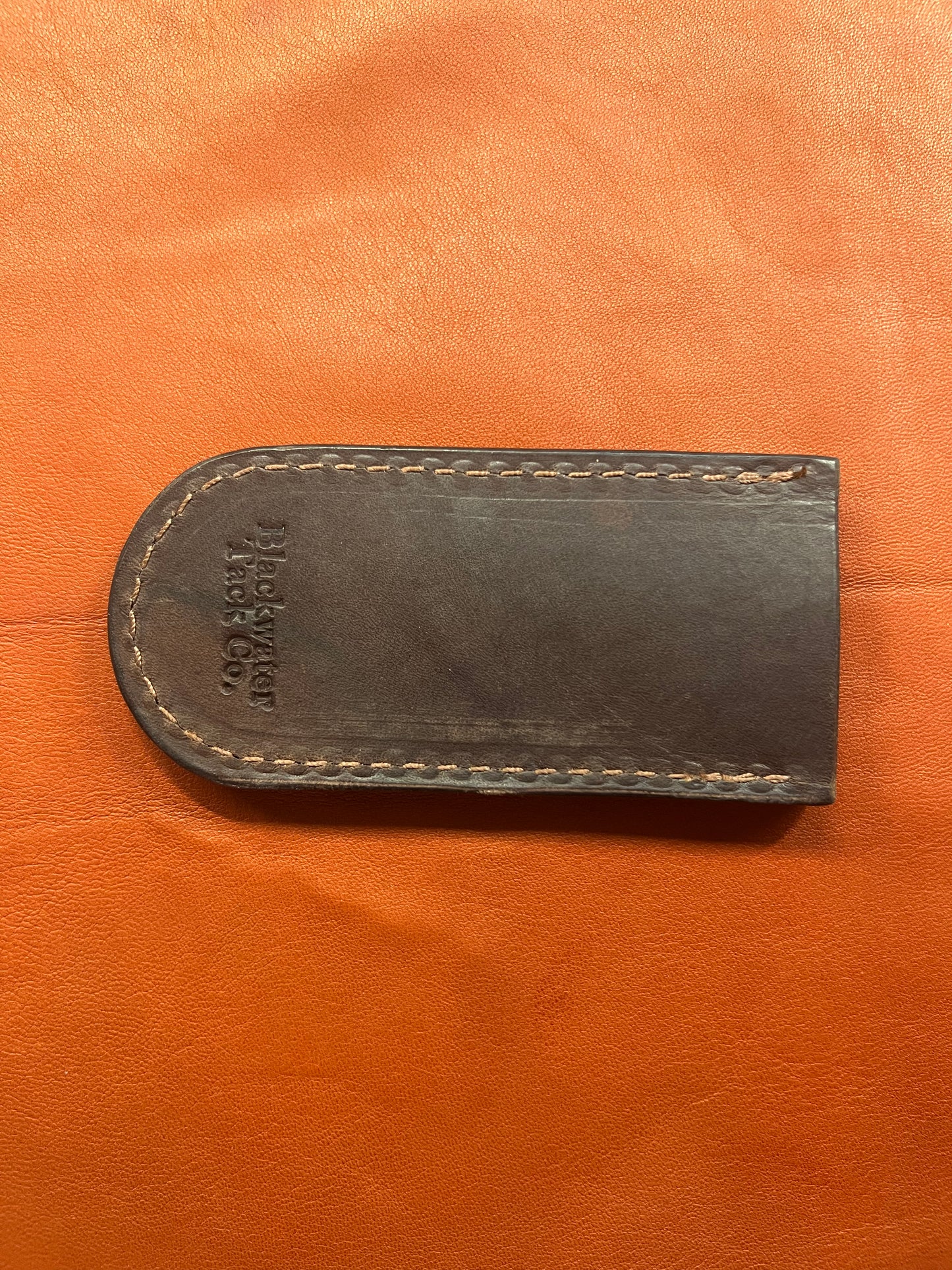 the back of a brown cast iron skillet handle cover featuring the blackwater tack company logo