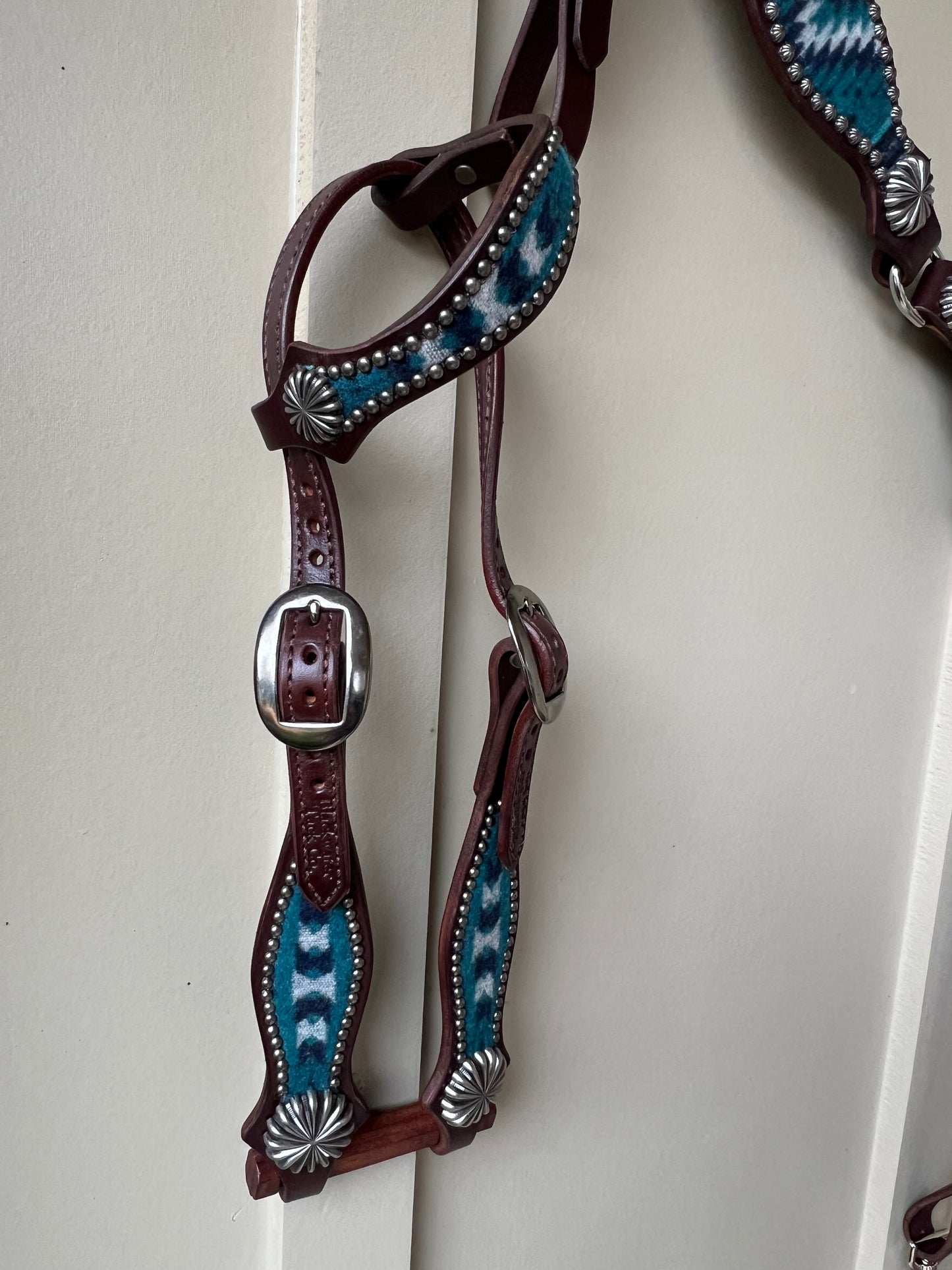 a headstall with wool inlay, nickel plated spots, and nickel parachute style conchos