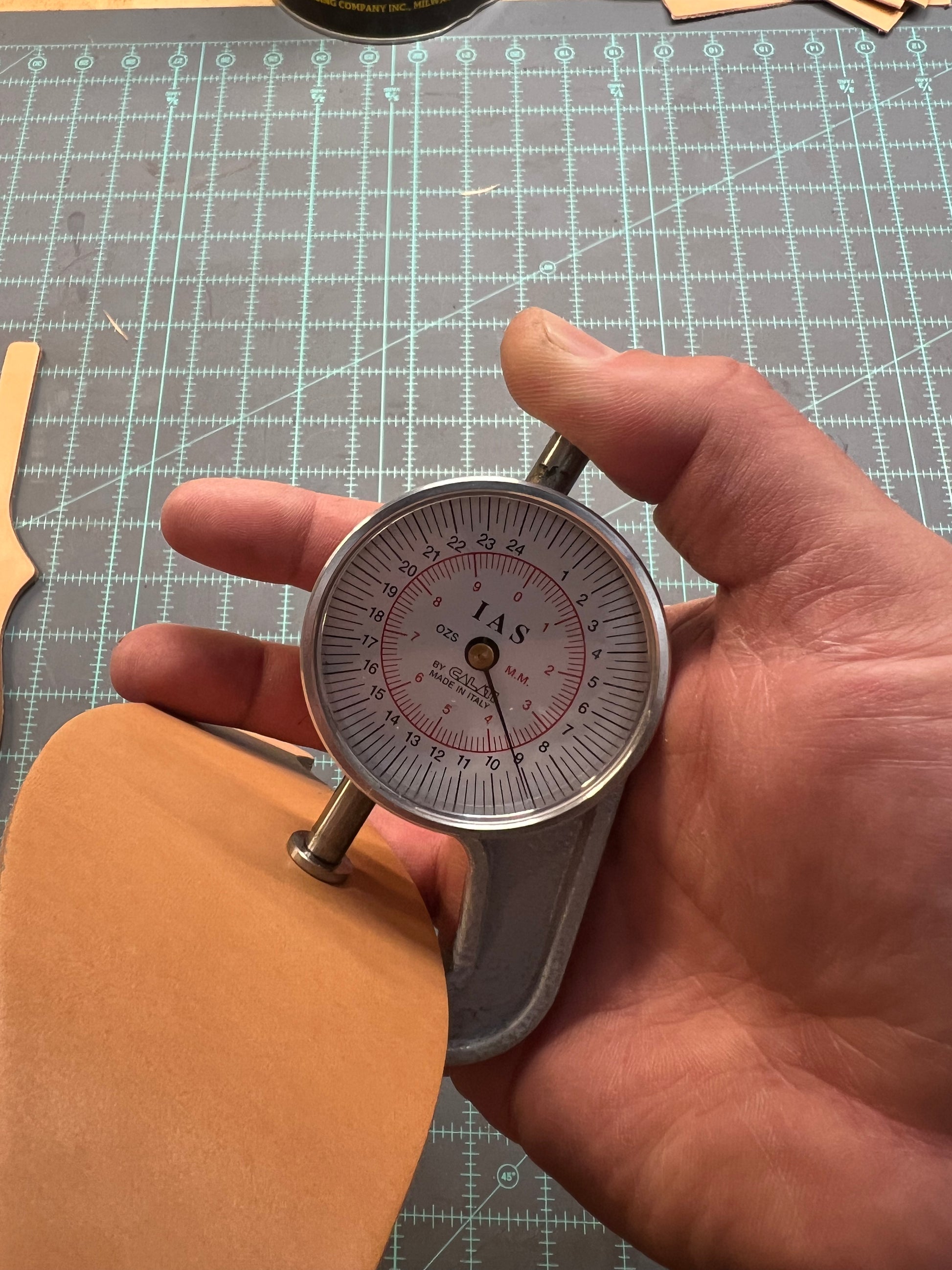 A man using a leather gauge to measure the thickness of a leather blank.