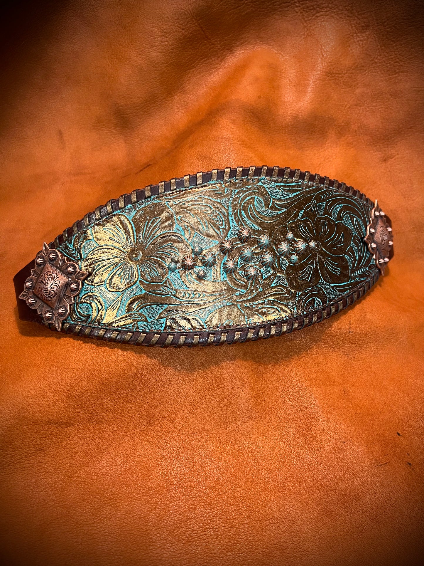 a noseband with teal and bronze embossed flowers, bronze spots, and bronze whipstitch