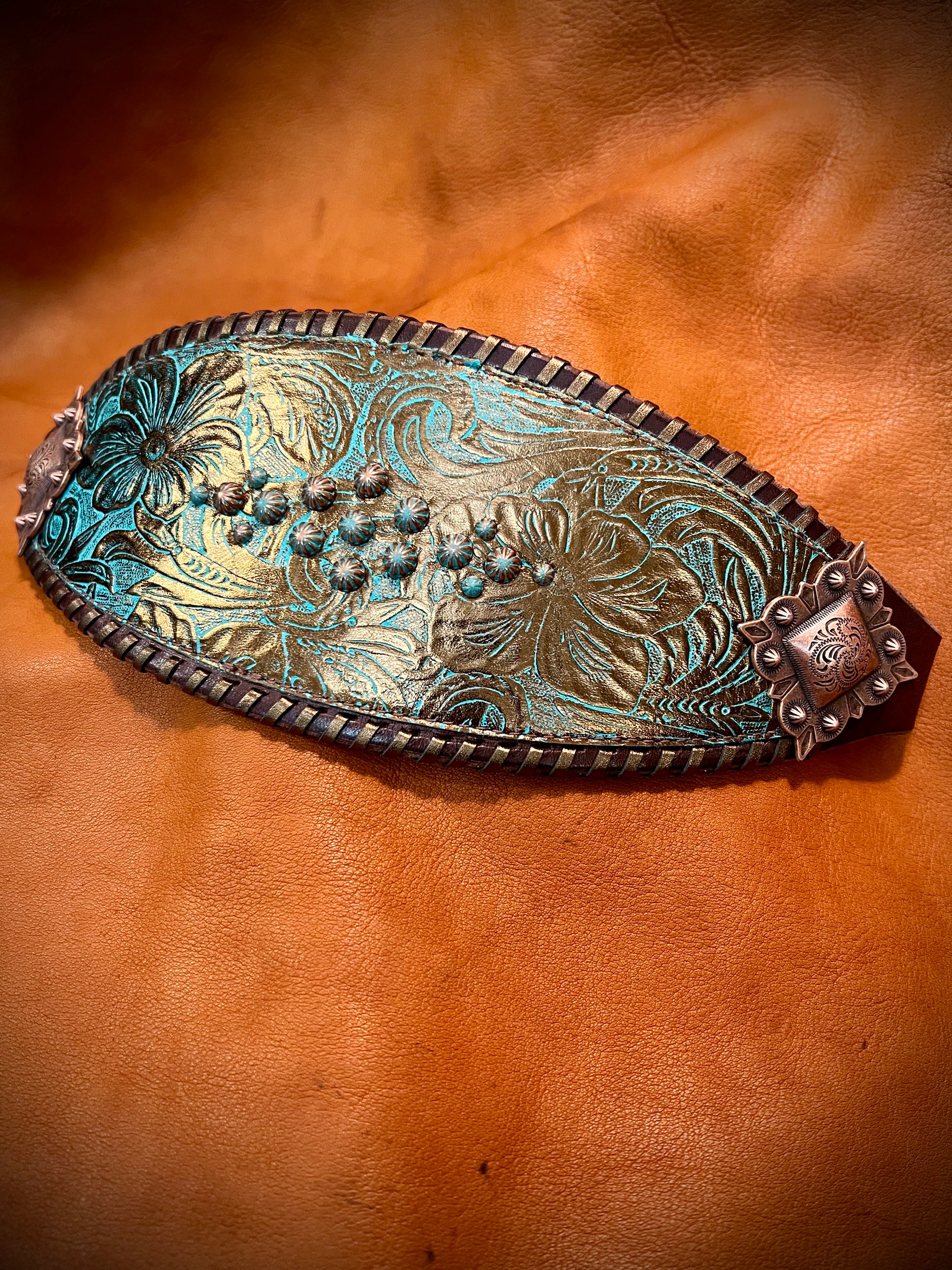 a noseband with teal and bronze embossed flowers, bronze spots, and bronze whipstitch