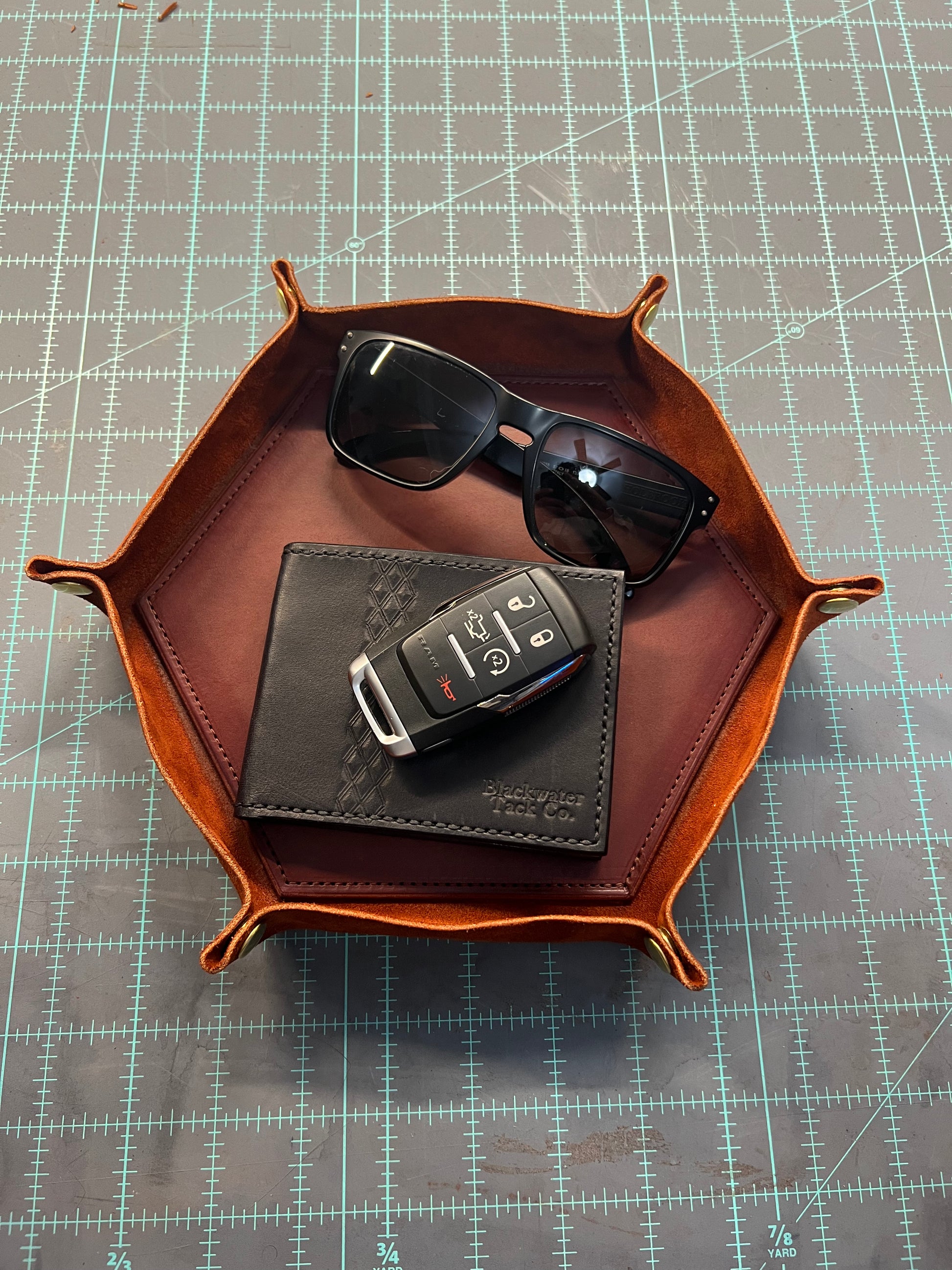 a leather valet tray with sunglasses, keys, and a wallet inside